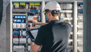 Engenheiro analisando projeto elétrico industrial em quadro de distribuição